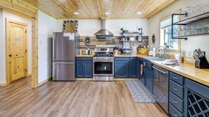 Une cuisine moderne avec un plafond en bois, des appareils électroménagers en acier inoxydable et un four encastré.