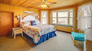 Una camera da letto con soffitto in legno, un letto con copriletto, un comodino, una finestra con vista e una panca finestra.