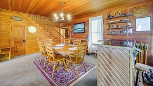 Un interno in legno con tavolo da pranzo, sedie, una scala e un'area bar.