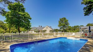A rectangular swimming pool with a white deck and metal ladder, surrounded by a white fence and trees. - Waterfront Cambridge Home: Pool & Dock! (Cambridge)