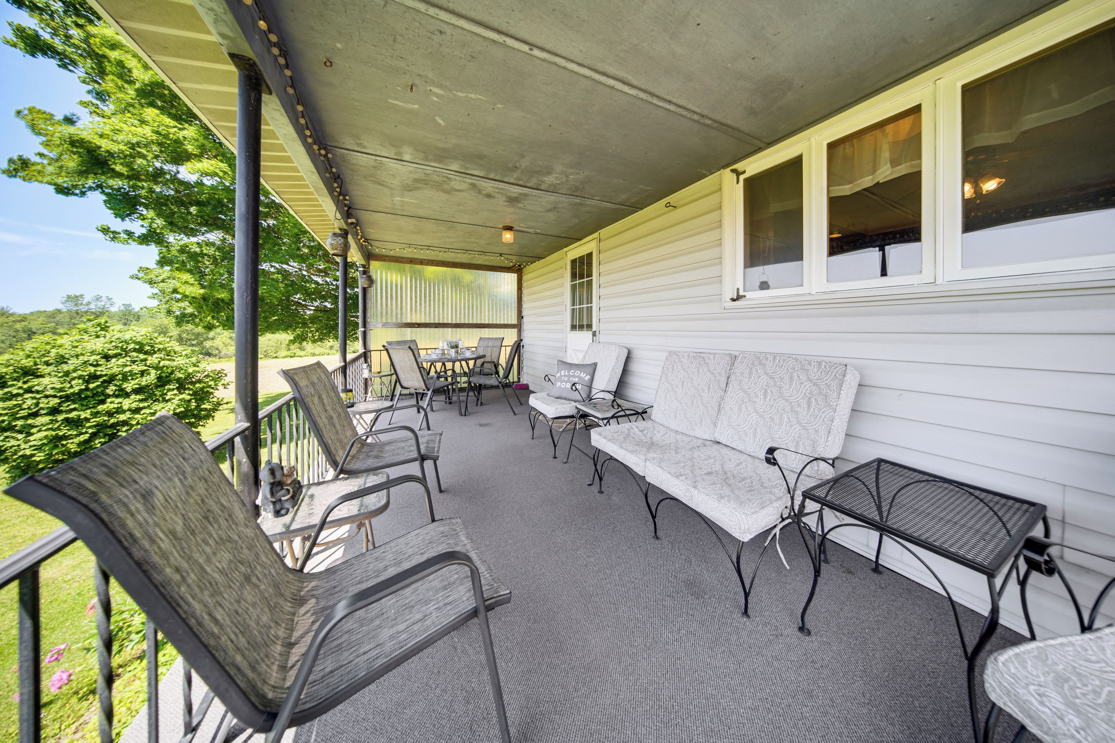 A covered porch with outdoor seating, a table, and chairs.