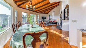 A dining area with a wooden ceiling, a long table with chairs, a chandelier, and a view of the outdoors. - Kelseyville Home w/ Deck & Clear Lake Views! (Kelseyville)