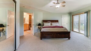 A bedroom with a large bed, a ceiling fan, and a view through a sliding glass door. - Kelseyville Home w/ Deck & Clear Lake Views! (Kelseyville)