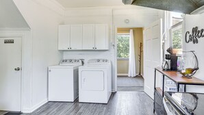 A laundry room with two white washing machines, a coffee station with a coffee maker and a glass, and a door labeled "Restricted Area." - Jackson Family Home ~ 5 Mi to Downtown! (Jackson)