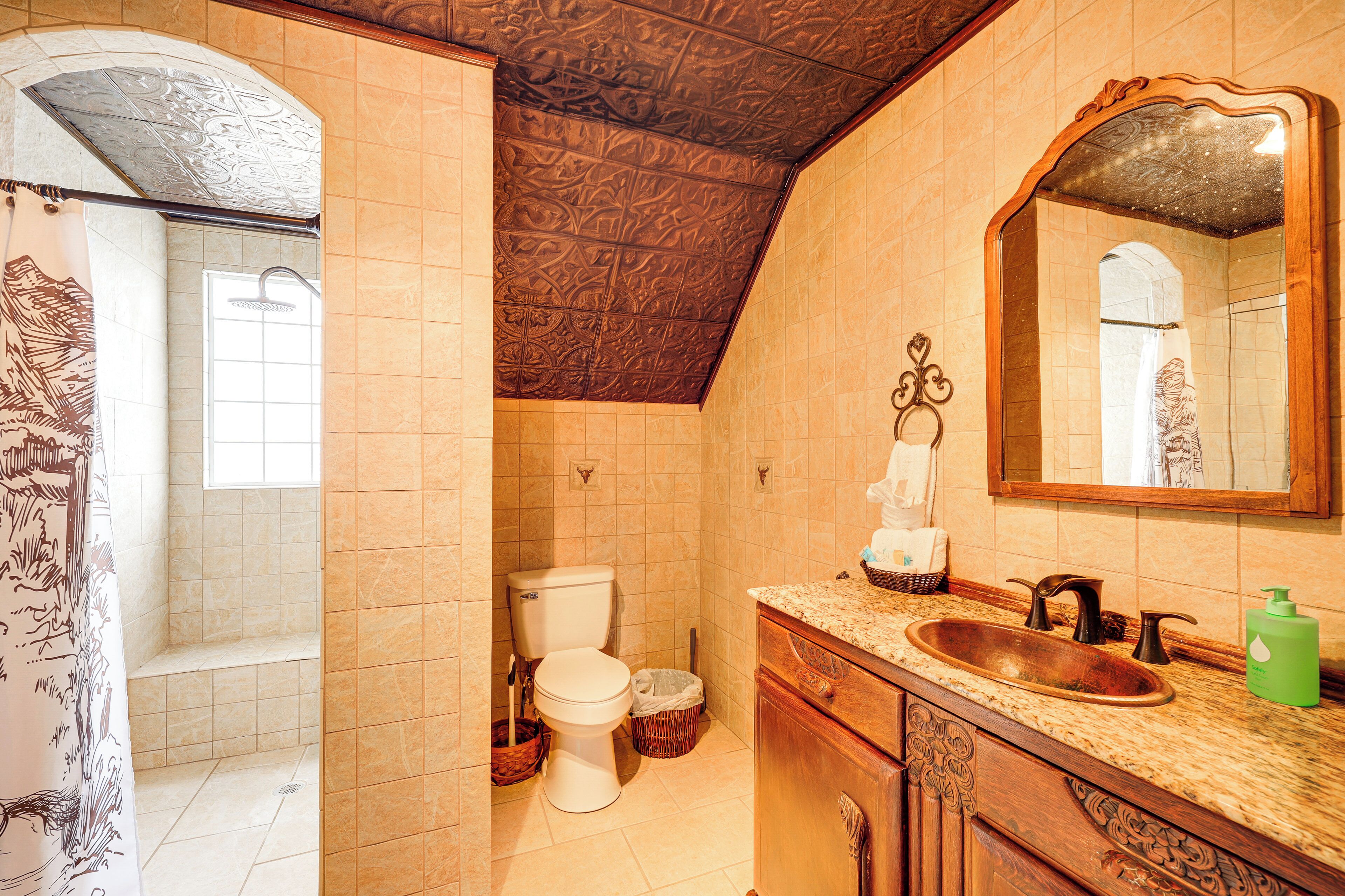 A bathroom with a shower, toilet, sink, and mirror.
