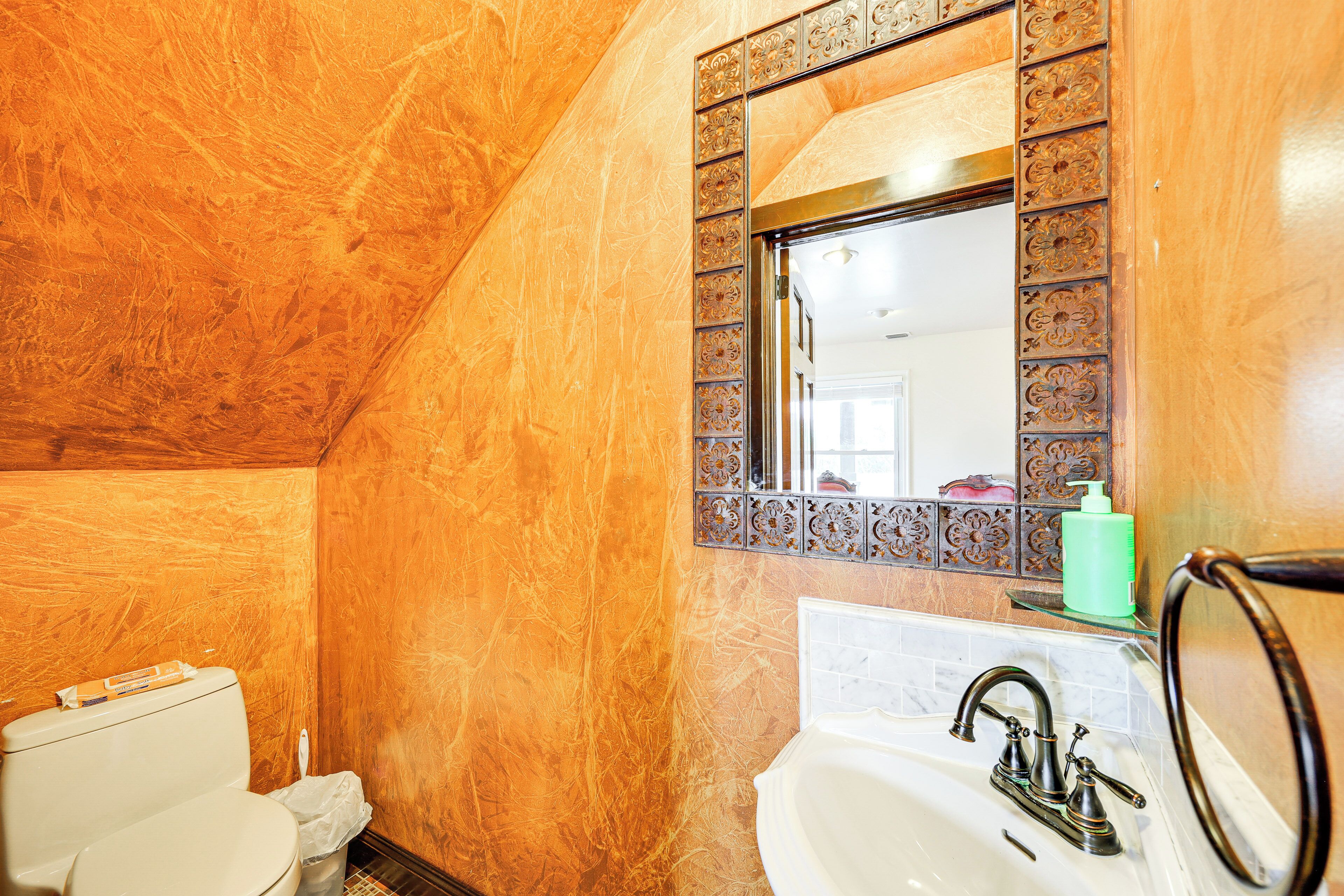 Un baño con pared de mármol, un lavamanos con grifo y un inodoro.
