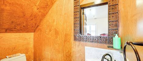 Un baño con pared de mármol, un lavamanos con grifo y un inodoro.