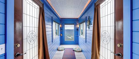 A hallway with blue walls, a wooden floor, and a view of the outdoors.