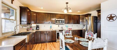 A kitchen with wooden cabinets, a stainless steel refrigerator, a microwave, and a dining table with chairs.