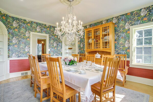 A dining room with a chandelier, wooden chairs, a table set for six, and a floral wallpaper. - On 7 Acres! Riverfront Estate w/ Views in Denton (Denton)