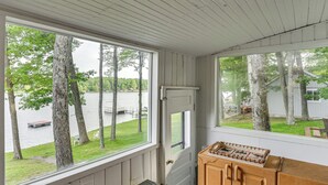 Una habitación con techo de madera y ventanas amplias que dan a un lago y árboles.