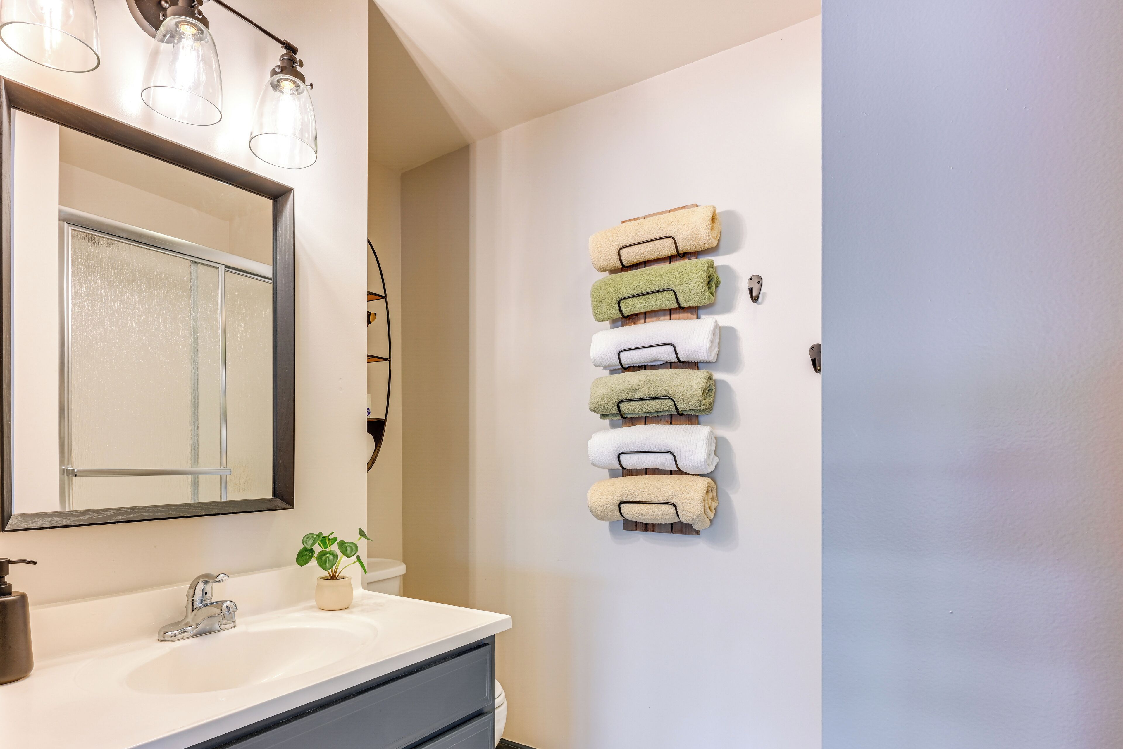 A bathroom with a white sink, a mirror, and a towel rack with multiple towels.