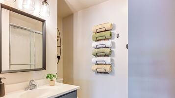 A bathroom with a white sink, a mirror, and a towel rack with multiple towels.