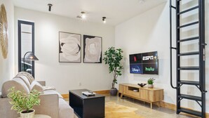 Una sala de estar moderna con un sofá, una mesa de centro y un televisor en la pared que muestra los logotipos de ESPN+ y Hulu.