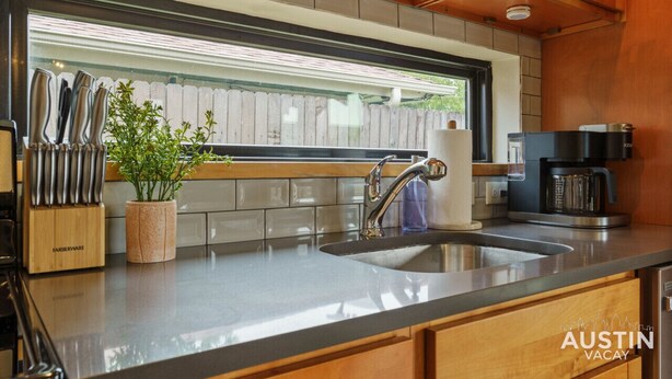 Una cocina moderna con un lavamanos de acero inoxidable, una cafetera y un bloque de cuchillos.
