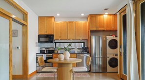 A modern kitchen with wooden cabinets, stainless steel appliances, and a central island with chairs. - Caddie St #A xxxxxxx (Austin)