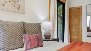 Un dormitorio con cama, almohadas, una lámpara y una puerta.