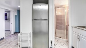 A modern kitchen with white cabinets, a stainless steel refrigerator, and a marble-tiled floor. - Convenient Apt: 2 Mi to Sprain Ridge Park! (Yonkers)