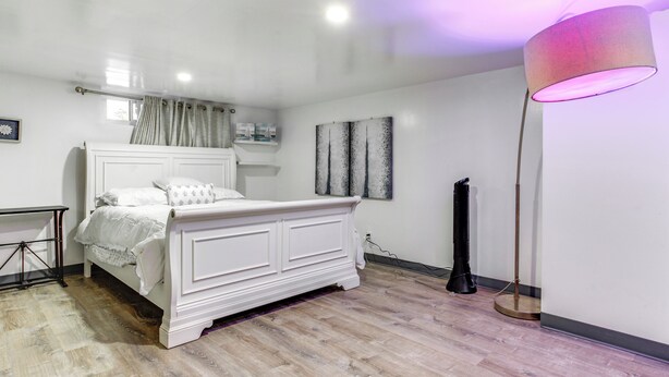 A bedroom with a white bed, a standing lamp, and a floor lamp. - Convenient Apt: 2 Mi to Sprain Ridge Park! (Yonkers)