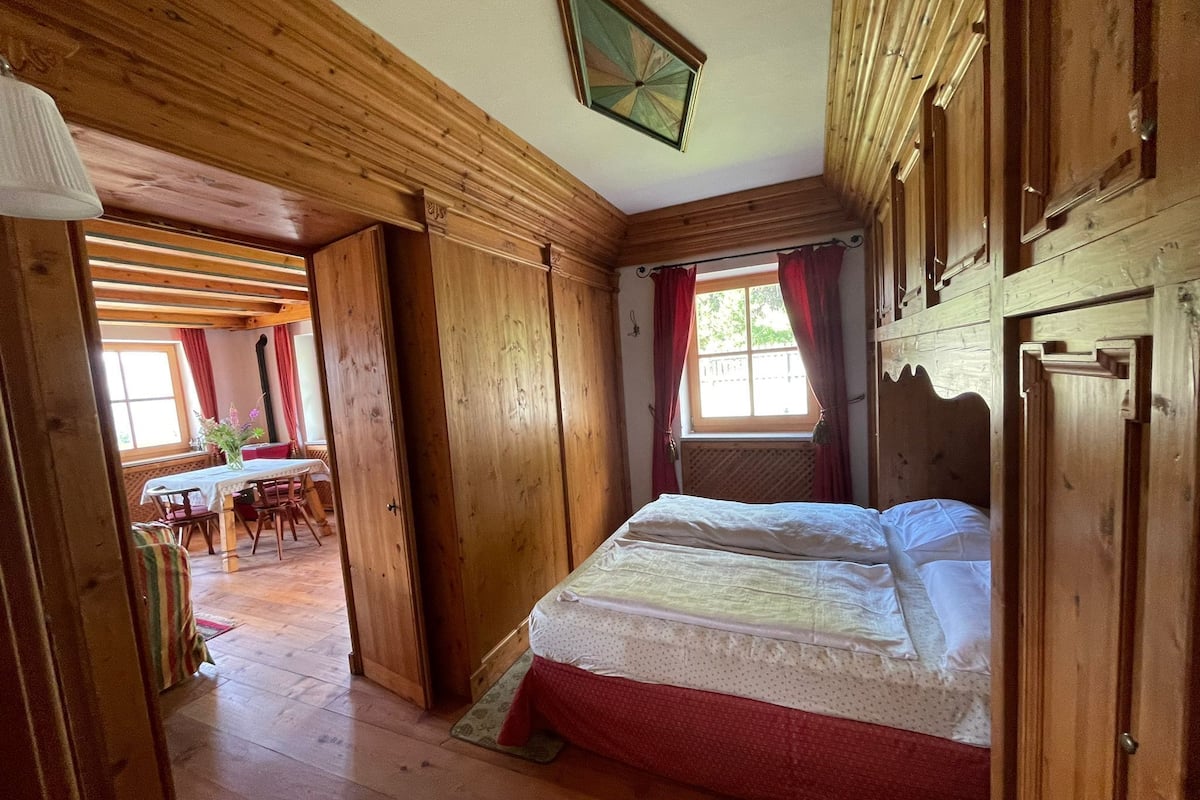 A wooden room with a bed, a table, and chairs.