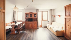 Une pièce chaleureuse avec une table à manger en bois, des chaises, un canapé et un meuble contenant un téléviseur.
