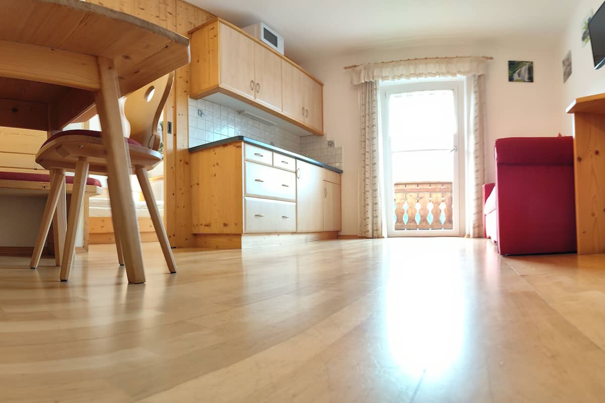 A spacious kitchen with wooden cabinets, a dining table, and a red refrigerator.