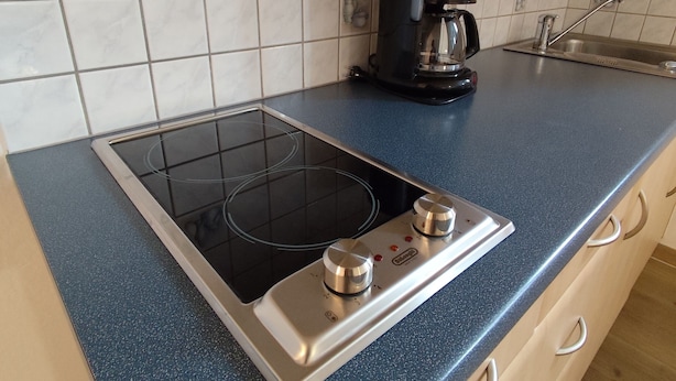 Une cuisine avec une plaque de cuisson noire, une machine à café et un évier.