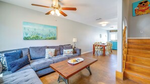 A living room with a sectional sofa, a wooden coffee table, a ceiling fan, and a painting on the wall. - Steps to Beach & Pool Access: Port Aransas Condo (Port Aransas)