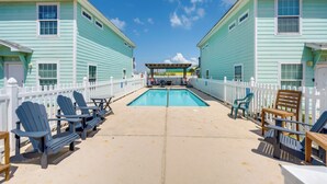 A pool area with lounge chairs and a pergola. - Steps to Beach & Pool Access: Port Aransas Condo (Port Aransas)