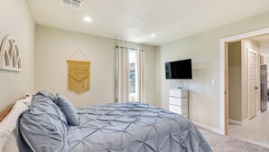 Una camera da letto con un letto, una TV, un armadio e una porta che dà su un'altra stanza.