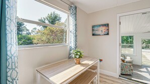 A room with a wooden table, a bench, a potted plant, a painting, and a view of the outdoors. - Chic Port Charlotte Home ~ 9 Mi to Englewood Beach (Port Charlotte)
