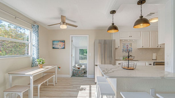 A modern kitchen with white cabinets, a large island, and pendant lighting. - Chic Port Charlotte Home ~ 9 Mi to Englewood Beach (Port Charlotte)
