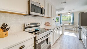 A modern kitchen with white cabinetry, stainless steel appliances, and a tiled backsplash. - Chic Port Charlotte Home ~ 9 Mi to Englewood Beach (Port Charlotte)