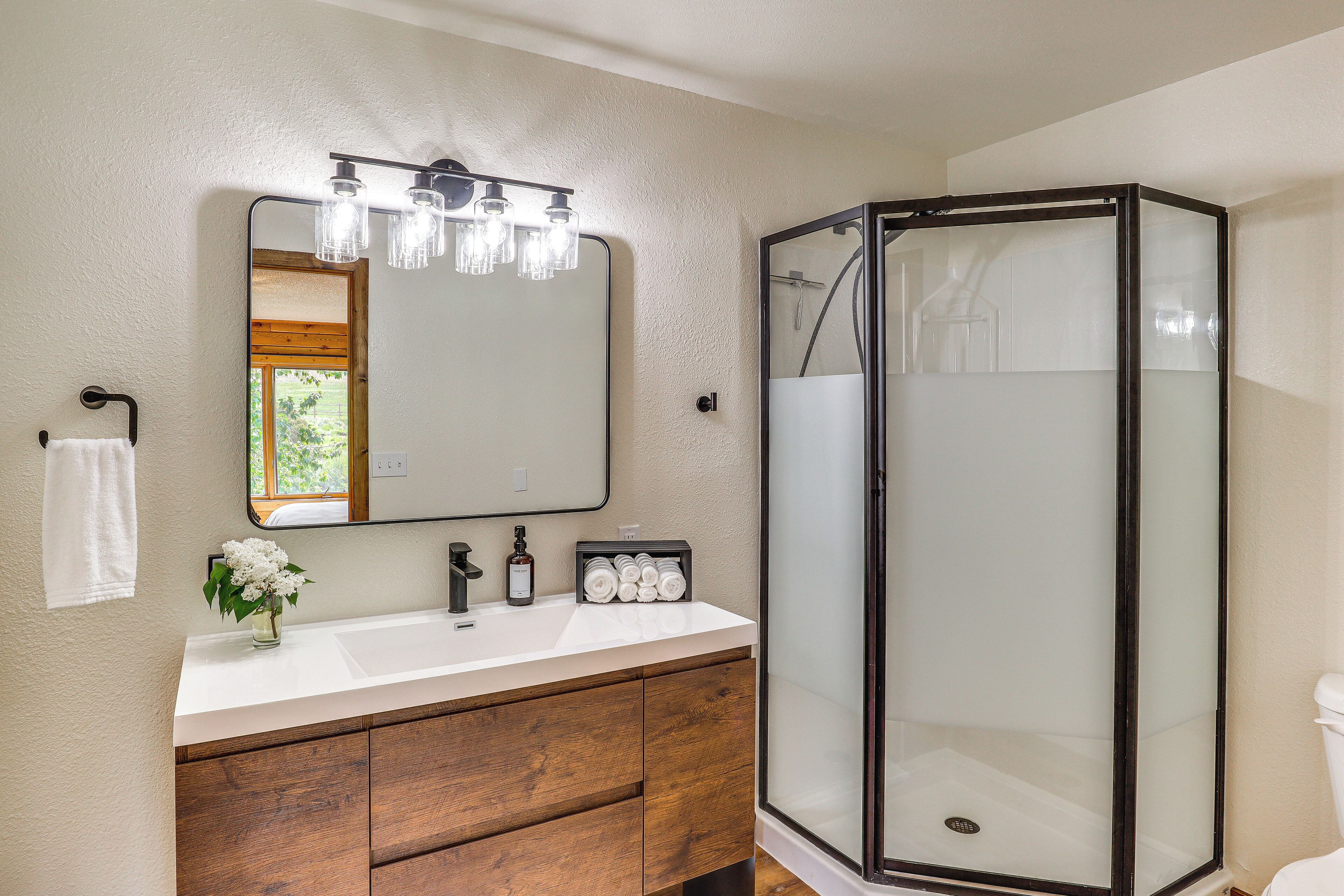 A bathroom with a white vanity, a large mirror, and a glass-enclosed shower.