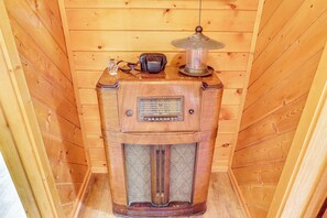 A vintage wooden radio with a decorative top and a small figurine beside it.