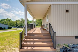 A covered porch with a wooden deck leading to a building with white siding.