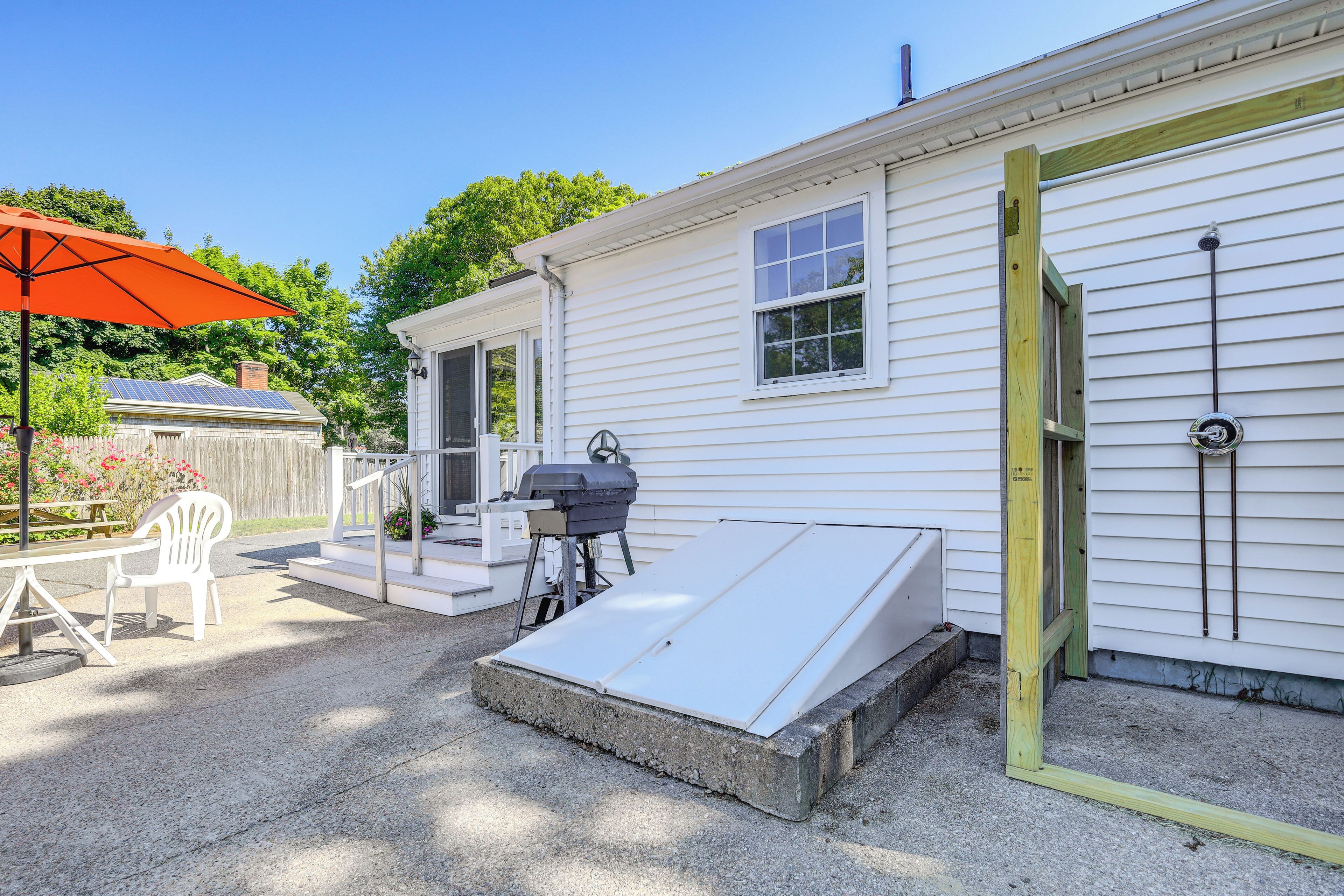 A white mobile home with a patio area, a barbecue grill, and a small deck.