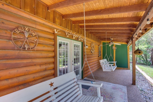 A log cabin with a porch, a swing chair, a bench, and antler decorations.