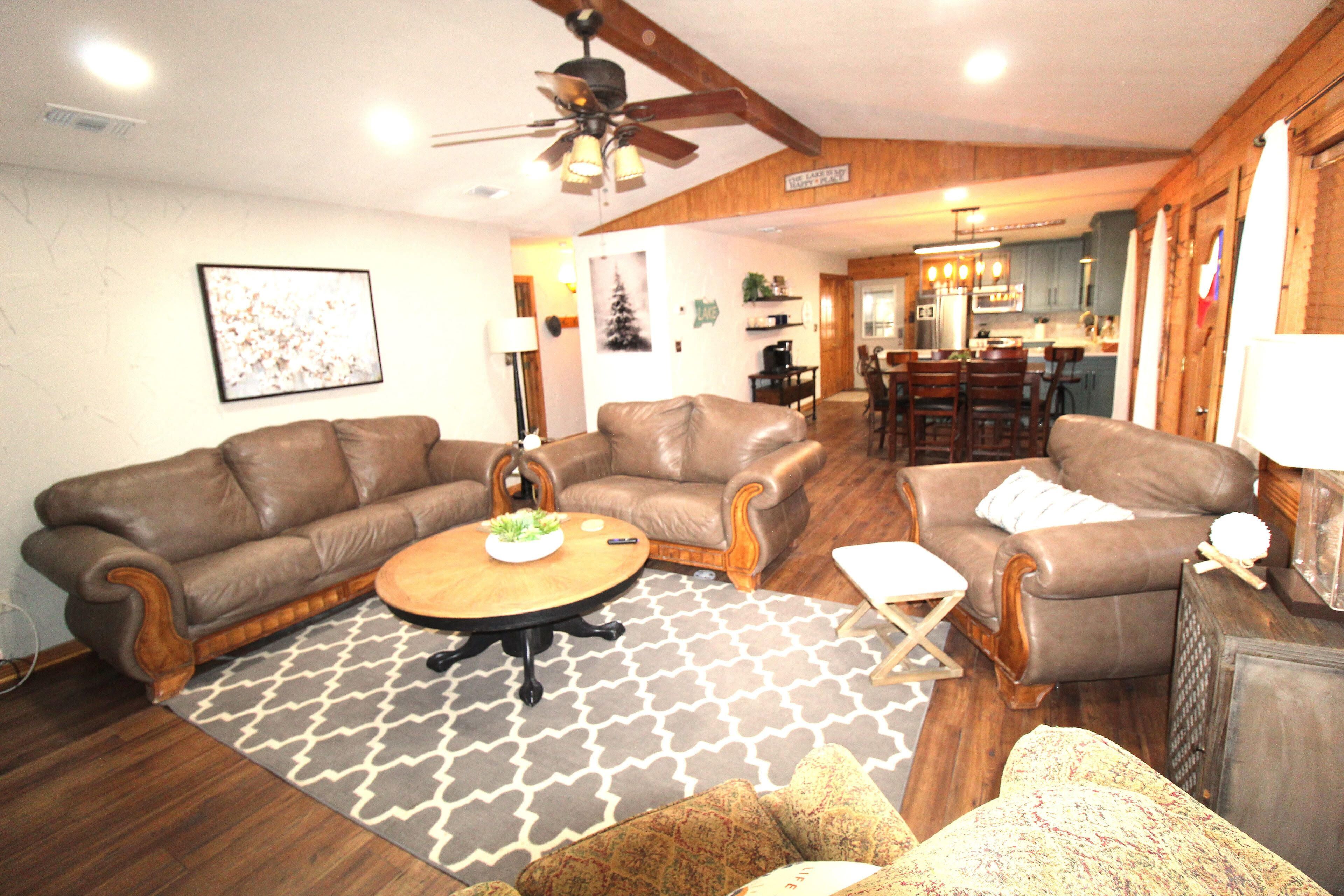 A spacious living room with two brown leather sofas, a wooden coffee table, and a patterned rug.