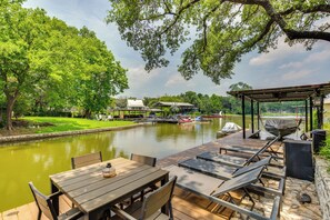 A wooden deck with tables and chairs overlooking a calm river, surrounded by lush greenery and a gazebo. - Granbury Home w/ Waterfront Deck: 5 Mi to Downtown (Granbury)