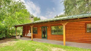 A log cabin with a porch, a swing, and a stone fireplace.