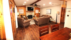 A cozy living room with a fireplace, leather sofas, and a dining table.