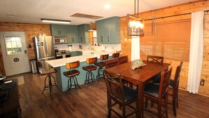 A kitchen with wooden cabinets, a central island with bar stools, and a dining table with chairs.