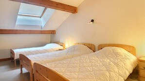 Ein Zimmer mit zwei Holzbett, einem Oberlicht und einem kleinen Nachttisch mit Lampe.