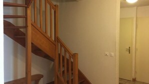 Eine Holztreppe in einem Raum mit weißen Wänden und einer Tür im Hintergrund.