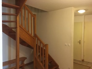 A wooden staircase in a room with white walls and a door in the background.