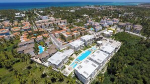Vista aérea de un resort con varias construcciones, una piscina y vistas al océano.