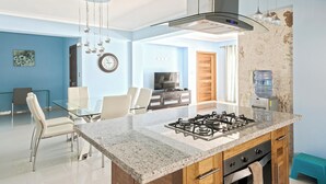 Una cocina moderna con estufa a gas, armarios de madera y un comedor con mesa y sillas de vidrio.