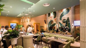 Un restaurant au décor moderne, comprenant un comptoir, un espace salon et des œuvres d’art décoratives murales.
