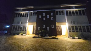Een gebouw met twee verdiepingen, een symmetrische gevel, grote ramen en een centrale ingang met een donkere deur.